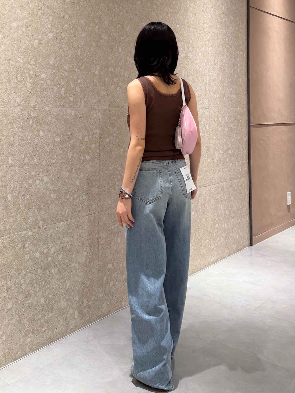 ブルー系のデニムパンツ、ブラック系のブーツ、ブラウン系のタンクトップを着用したレディースの夏コーディネートの4枚目の写真