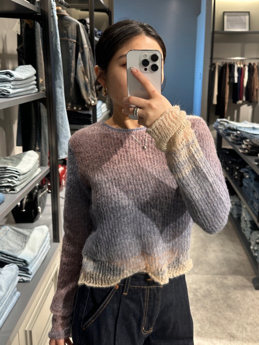 ブルー系のデニムパンツ、パープル系のニット/セーター、ブラック系のハンドバッグを着用したレディースの秋コーディネートの4枚目の写真