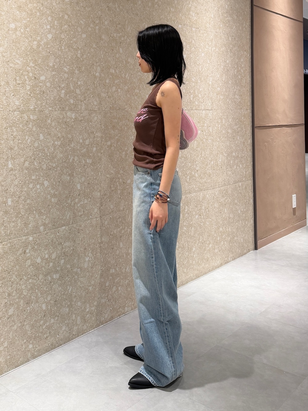 ブルー系のデニムパンツ、ブラック系のブーツ、ブラウン系のタンクトップを着用したレディースの夏コーディネートの3枚目の写真