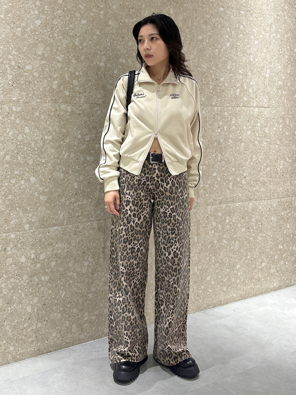 ホワイト系のジャージ、ブラウン系のデニムパンツ、ブラック系のブーツを着用したレディースの秋コーディネートの2枚目の写真