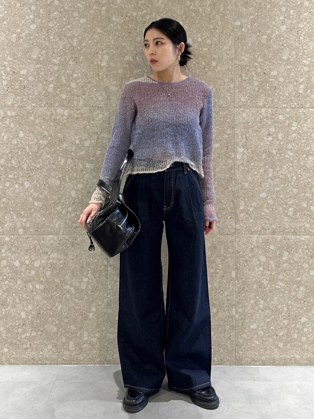 ブルー系のデニムパンツ、パープル系のニット/セーター、ブラック系のハンドバッグを着用したレディースの秋コーディネートの2枚目の写真