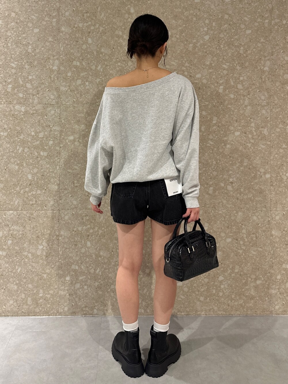 グレー系のスウェット、ブラック系のデニムパンツ、ブラック系のブーツを着用したレディースの秋コーディネートの3枚目の写真