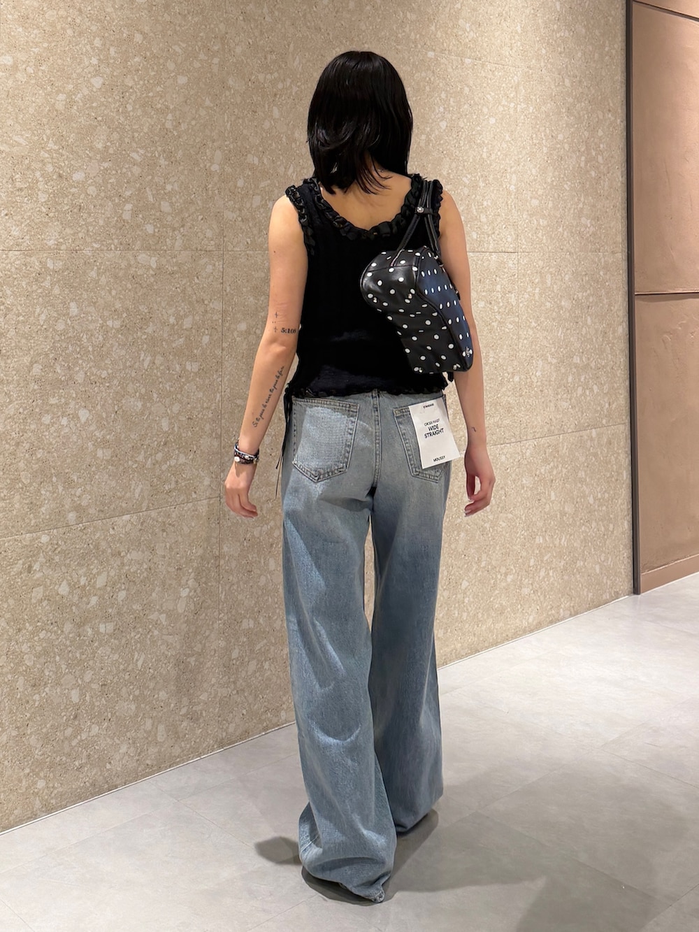 ブルー系のデニムパンツ、ブラック系のタンクトップ、ブラック系のブーツを着用したレディースの夏コーディネートの4枚目の写真