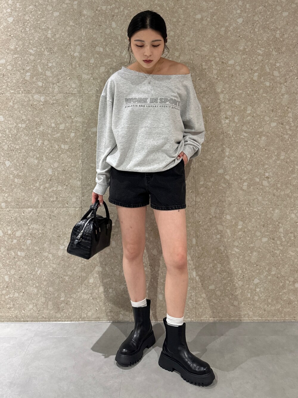グレー系のスウェット、ブラック系のデニムパンツ、ブラック系のブーツを着用したレディースの秋コーディネートの2枚目の写真