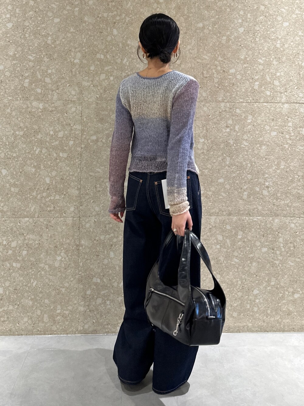 ブルー系のデニムパンツ、パープル系のニット/セーター、ブラック系のハンドバッグを着用したレディースの秋コーディネートの3枚目の写真