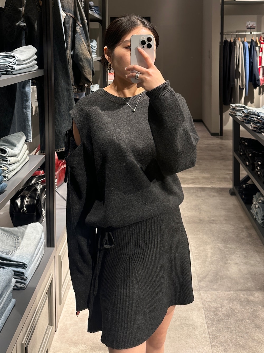 グレー系のワンピース、ブラック系のブーツ、ブラック系のショルダーバッグを着用したレディースの秋コーディネートの4枚目の写真