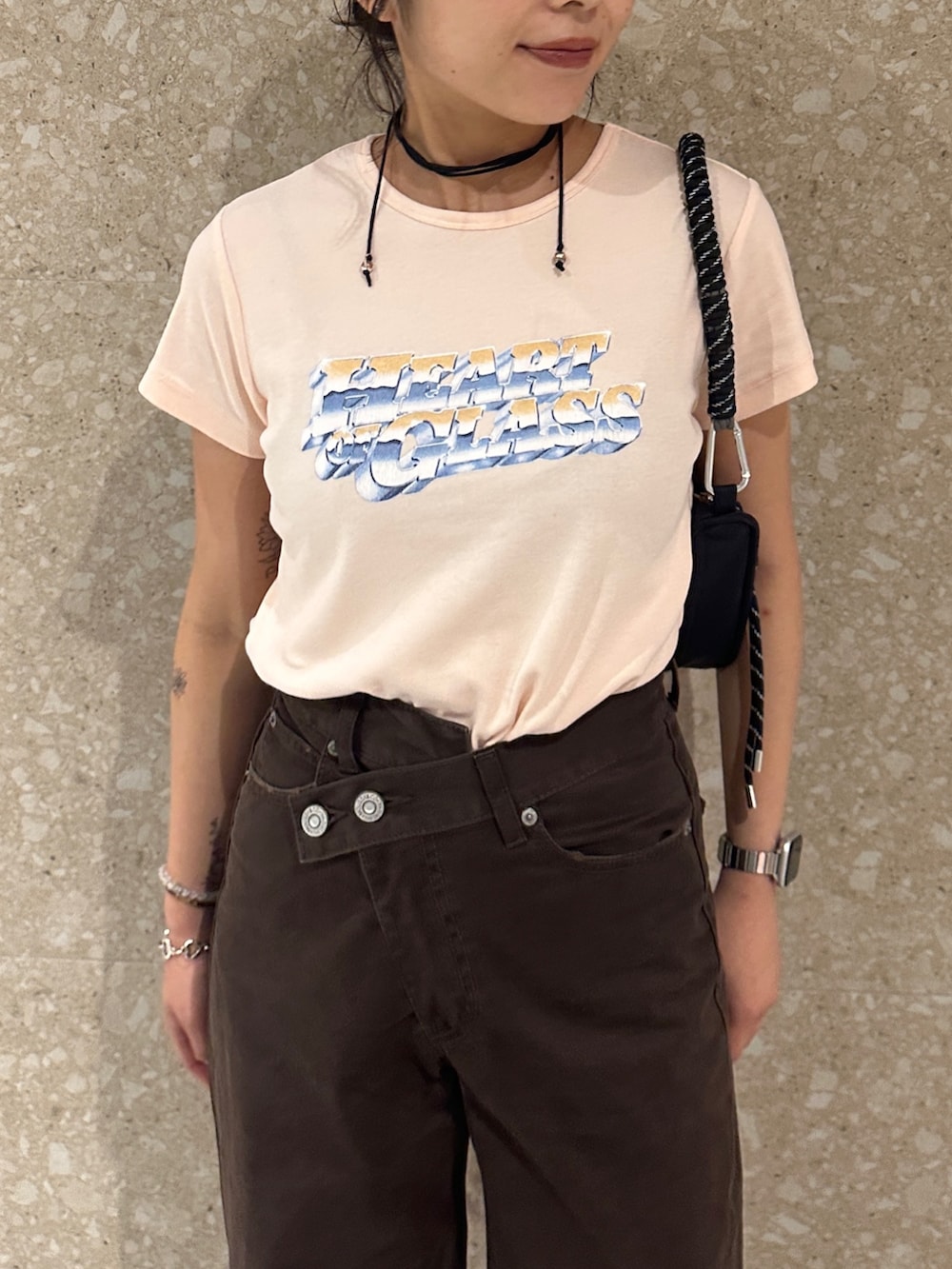 ブラウン系のチノパンツ、ブラック系のブーツ、オレンジ系のTシャツ/カットソーを着用したレディースの夏コーディネートの6枚目の写真