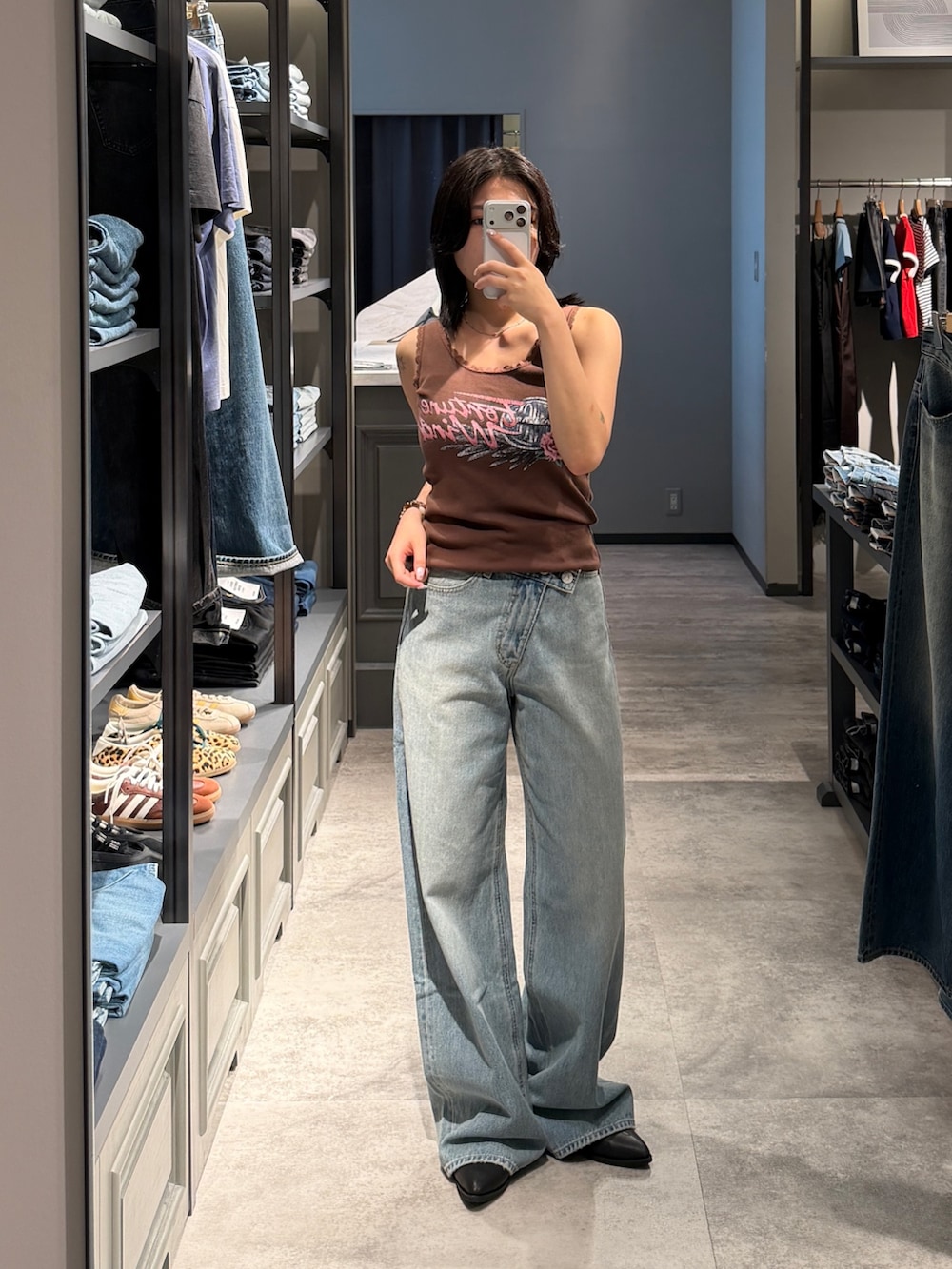 ブルー系のデニムパンツ、ブラック系のブーツ、ブラウン系のタンクトップを着用したレディースの夏コーディネートの6枚目の写真