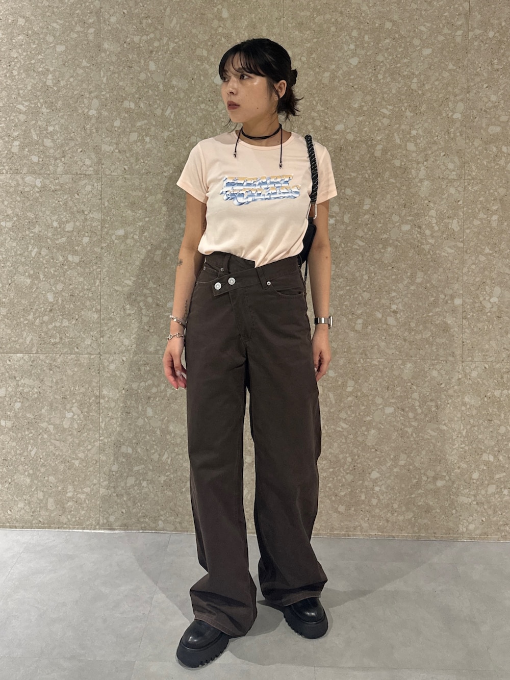 ブラウン系のチノパンツ、ブラック系のブーツ、オレンジ系のTシャツ/カットソーを着用したレディースの夏コーディネートの2枚目の写真