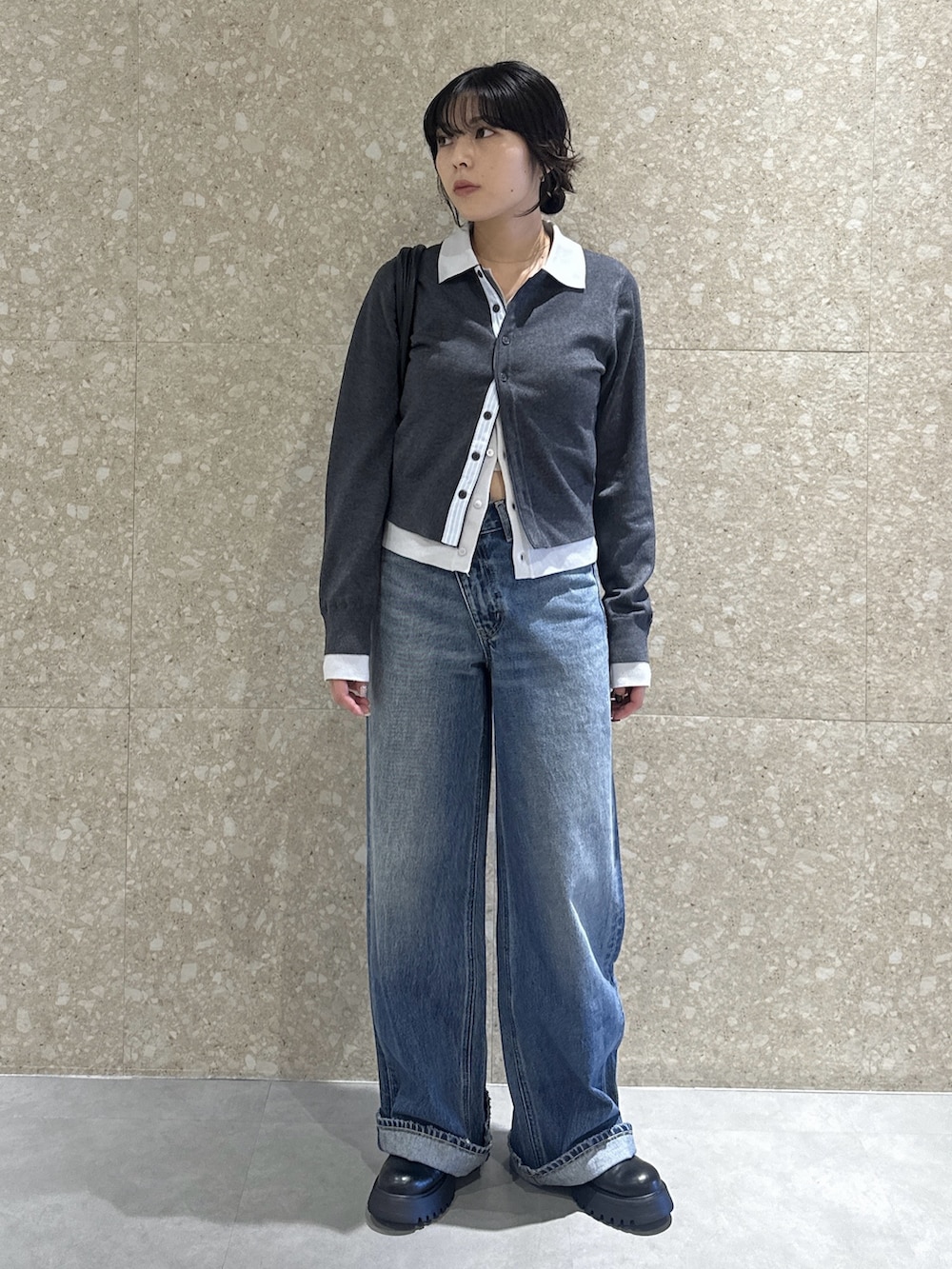 グレー系のニット/セーター、ブルー系のデニムパンツ、ブラック系のブーツを着用したレディースの秋コーディネートの2枚目の写真