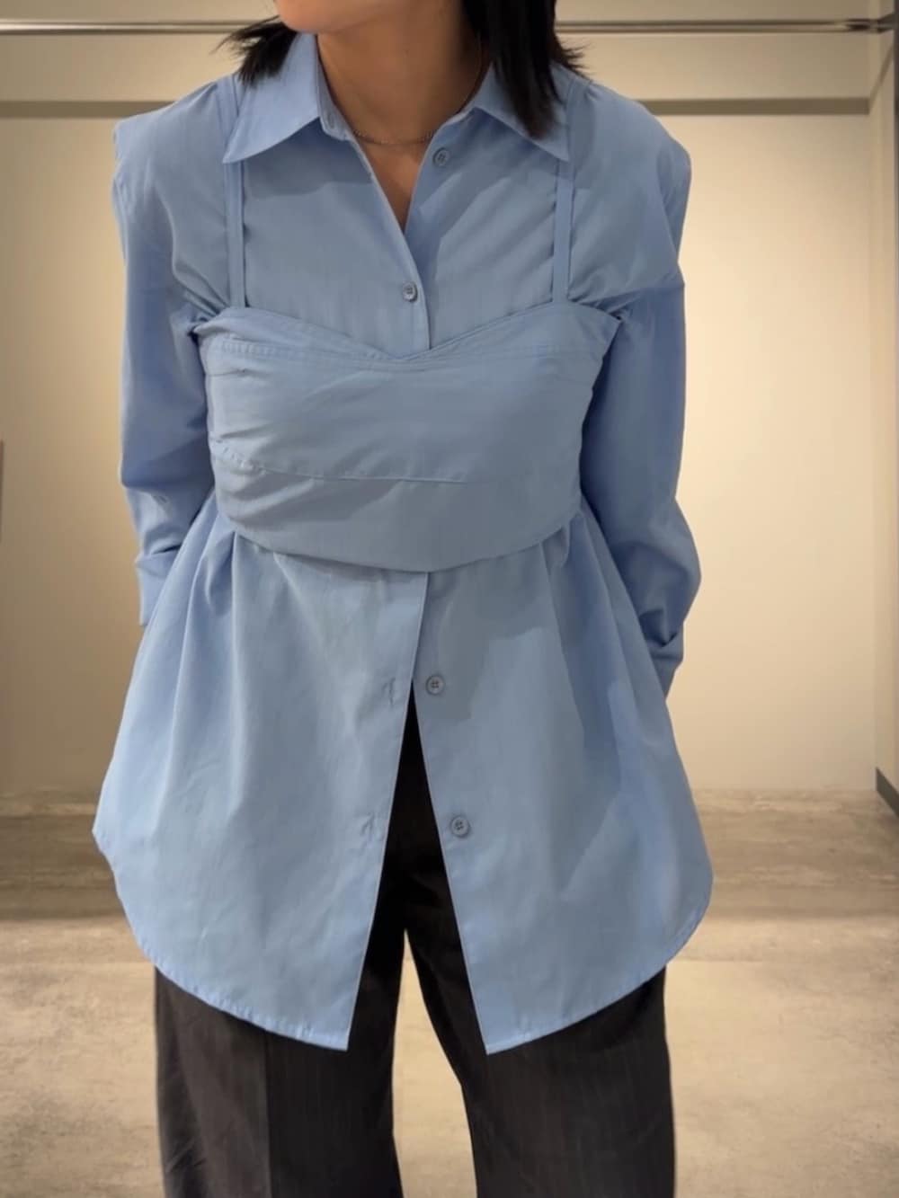 ブルー系のアンサンブル、グレー系のスラックス、ブラック系のショルダーバッグを着用したレディースの春コーディネートの6枚目の写真