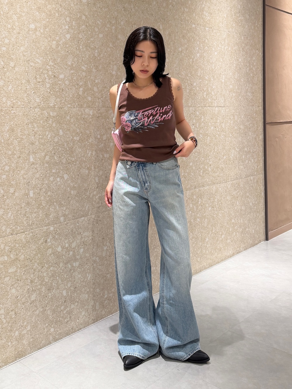 ブルー系のデニムパンツ、ブラック系のブーツ、ブラウン系のタンクトップを着用したレディースの夏コーディネートの2枚目の写真