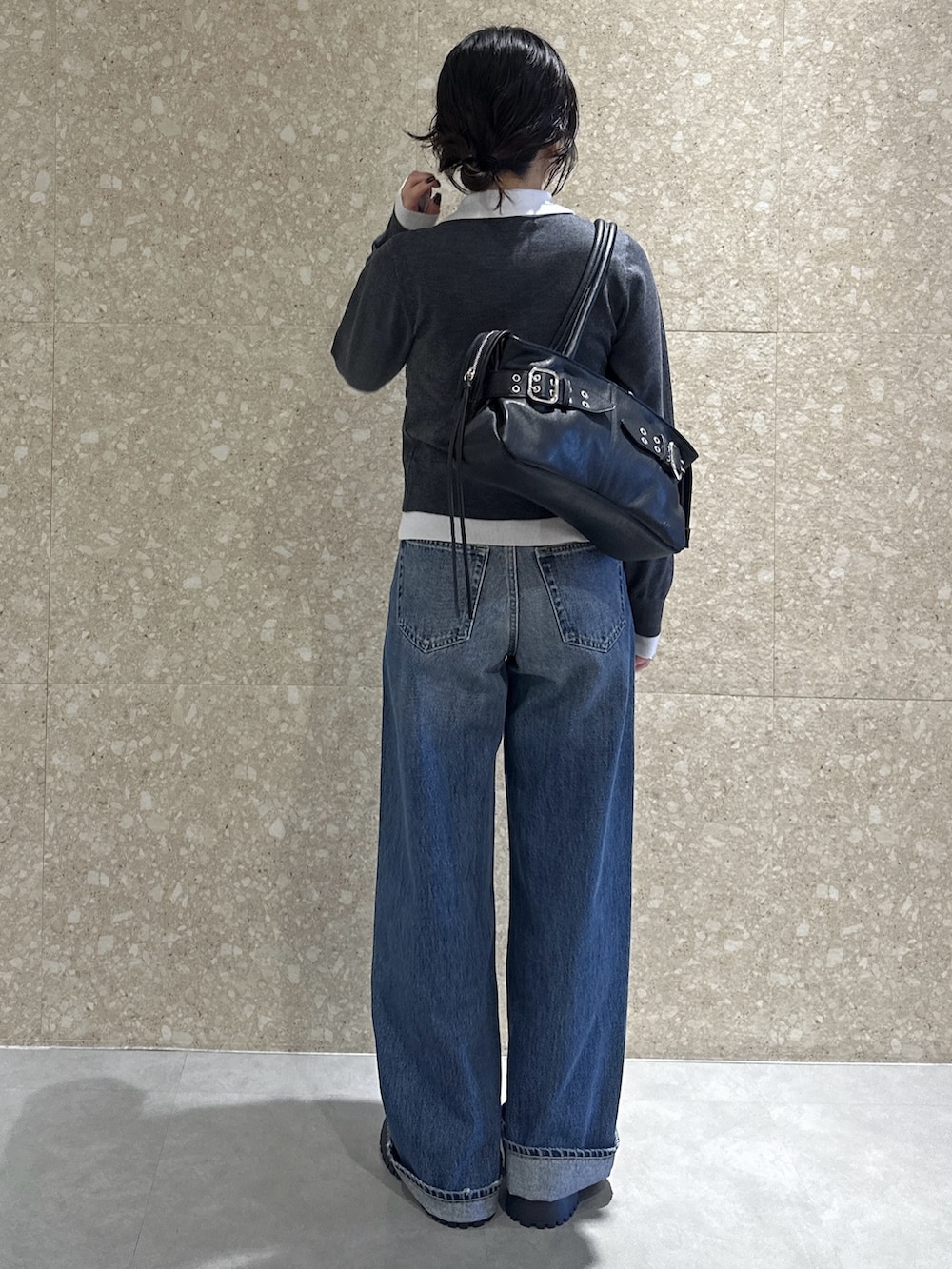 グレー系のニット/セーター、ブルー系のデニムパンツ、ブラック系のブーツを着用したレディースの秋コーディネートの4枚目の写真