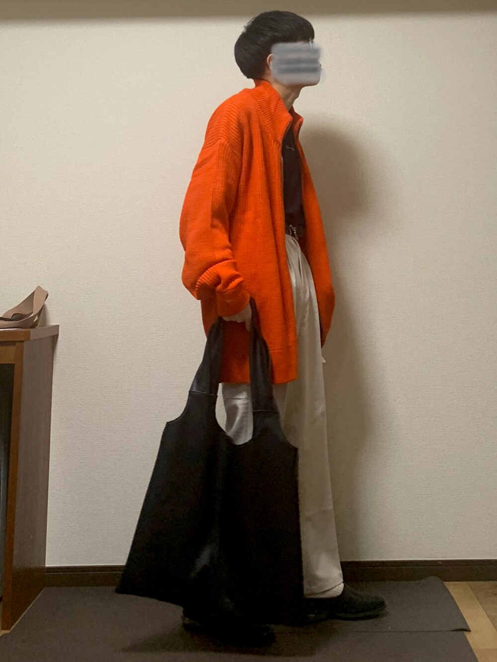 オレンジ系のニット/セーター、ブラック系のTシャツ/カットソー、ホワイト系のスラックスを着用したメンズの秋コーディネートの3枚目の写真