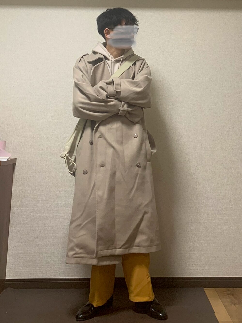 ホワイト系のパーカー、ベージュ系のステンカラーコート、ベージュ系のバッグを着用したメンズの秋コーディネートの2枚目の写真