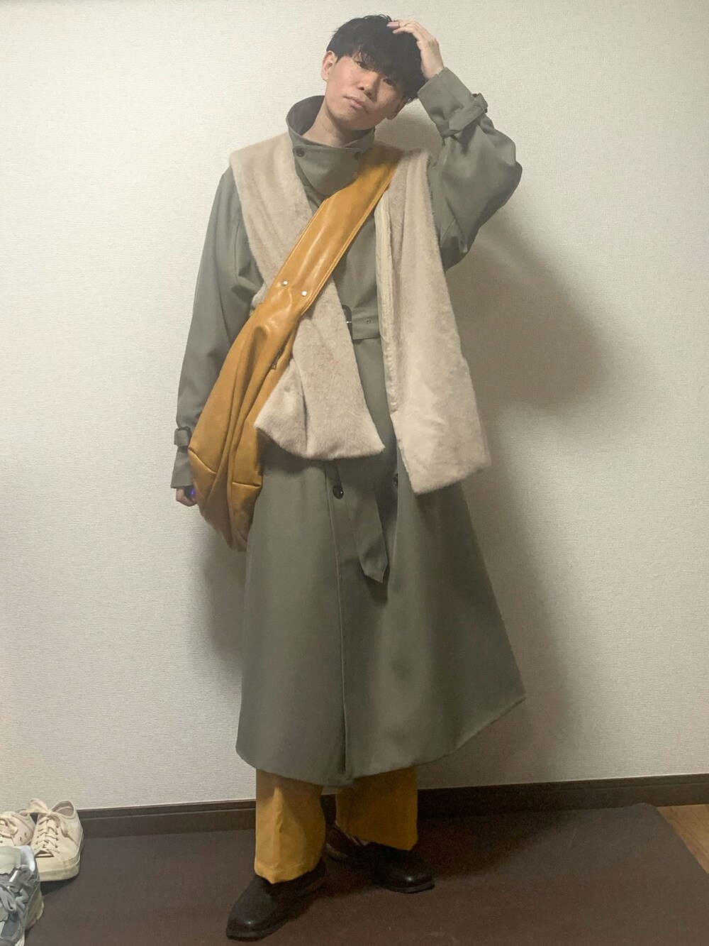 ベージュ系のベスト、ベージュ系のトレンチコート、イエロー系のショルダーバッグを着用したメンズの春コーディネートの2枚目の写真