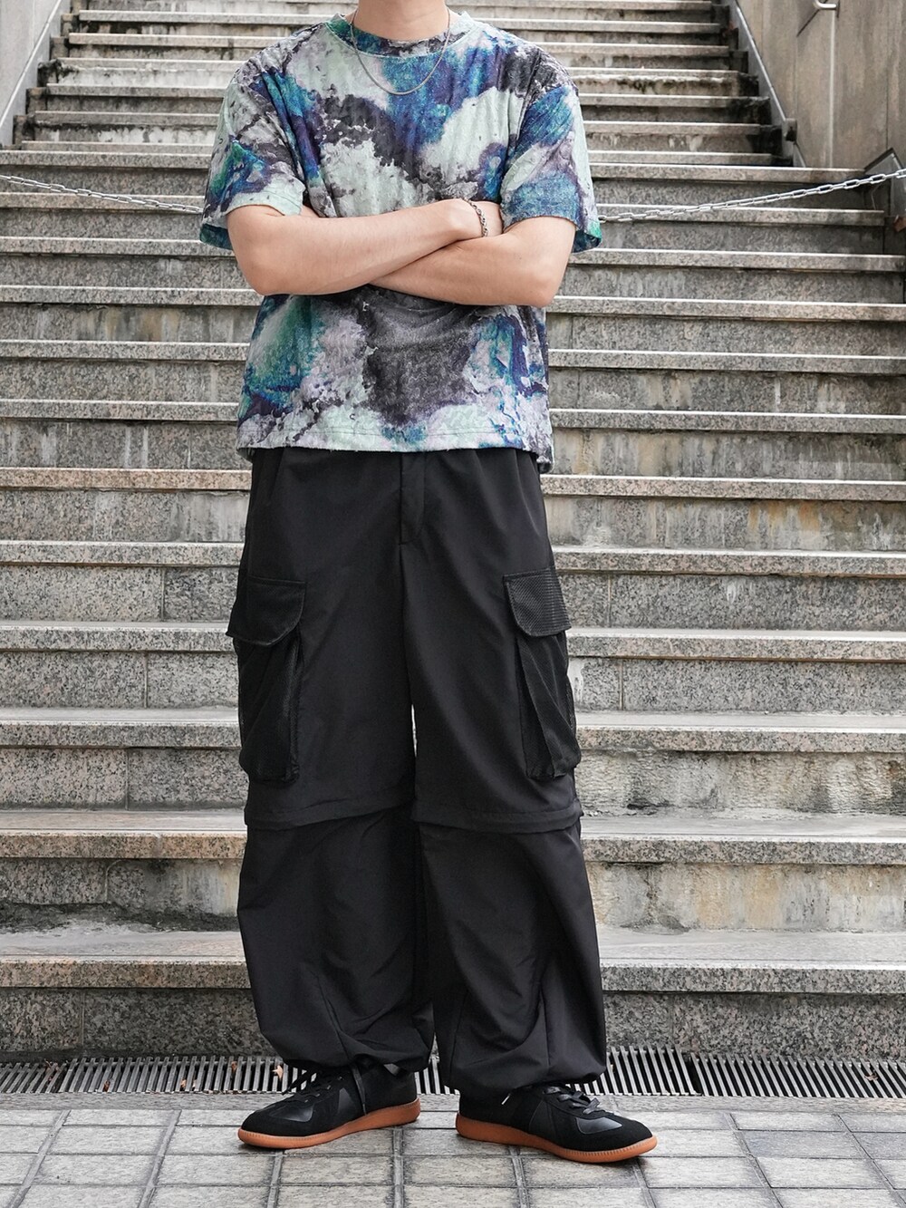 グリーン系のTシャツ/カットソー、ブラック系のカーゴパンツ、ブラック系のスニーカーを着用したメンズの夏コーディネートの3枚目の写真