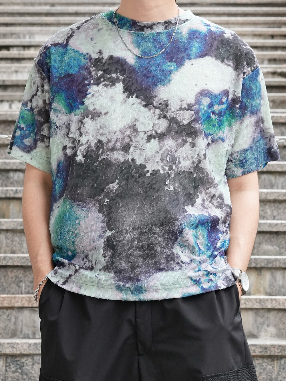 グリーン系のTシャツ/カットソー、ブラック系のカーゴパンツ、ブラック系のスニーカーを着用したメンズの夏コーディネートの2枚目の写真