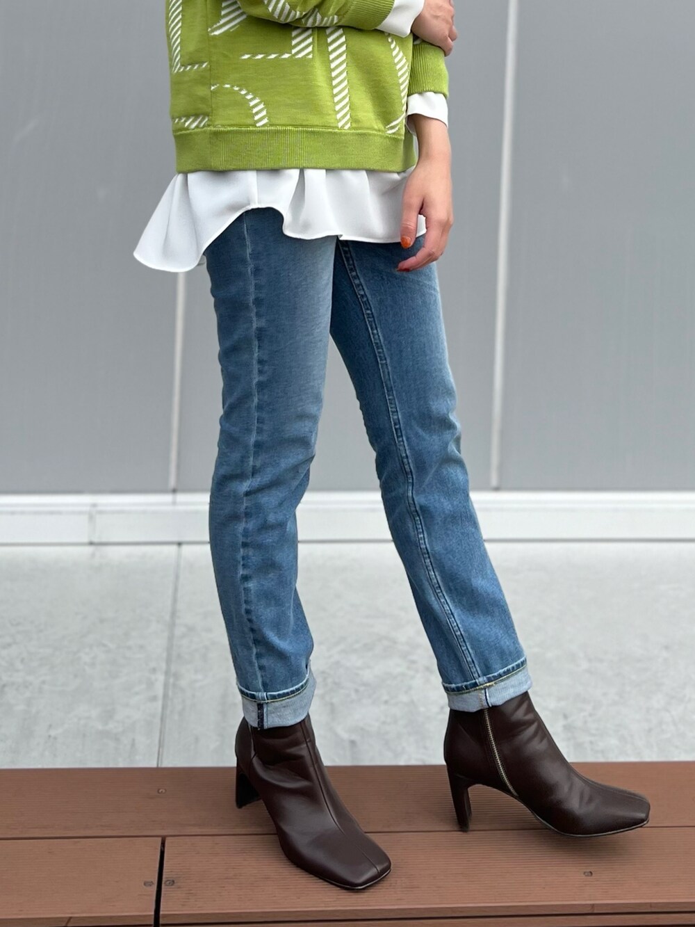 グリーン系のニット/セーター、グレー系のシャツ/ブラウス、ブルー系のデニムパンツを着用したレディースの冬コーディネートの4枚目の写真