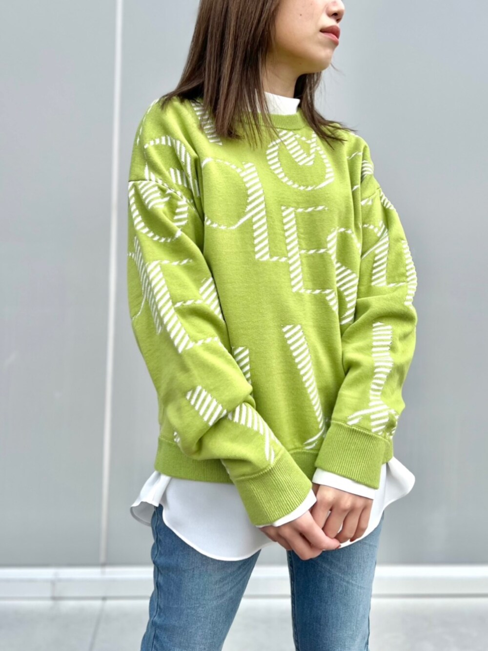 グリーン系のニット/セーター、グレー系のシャツ/ブラウス、ブルー系のデニムパンツを着用したレディースの冬コーディネートの3枚目の写真