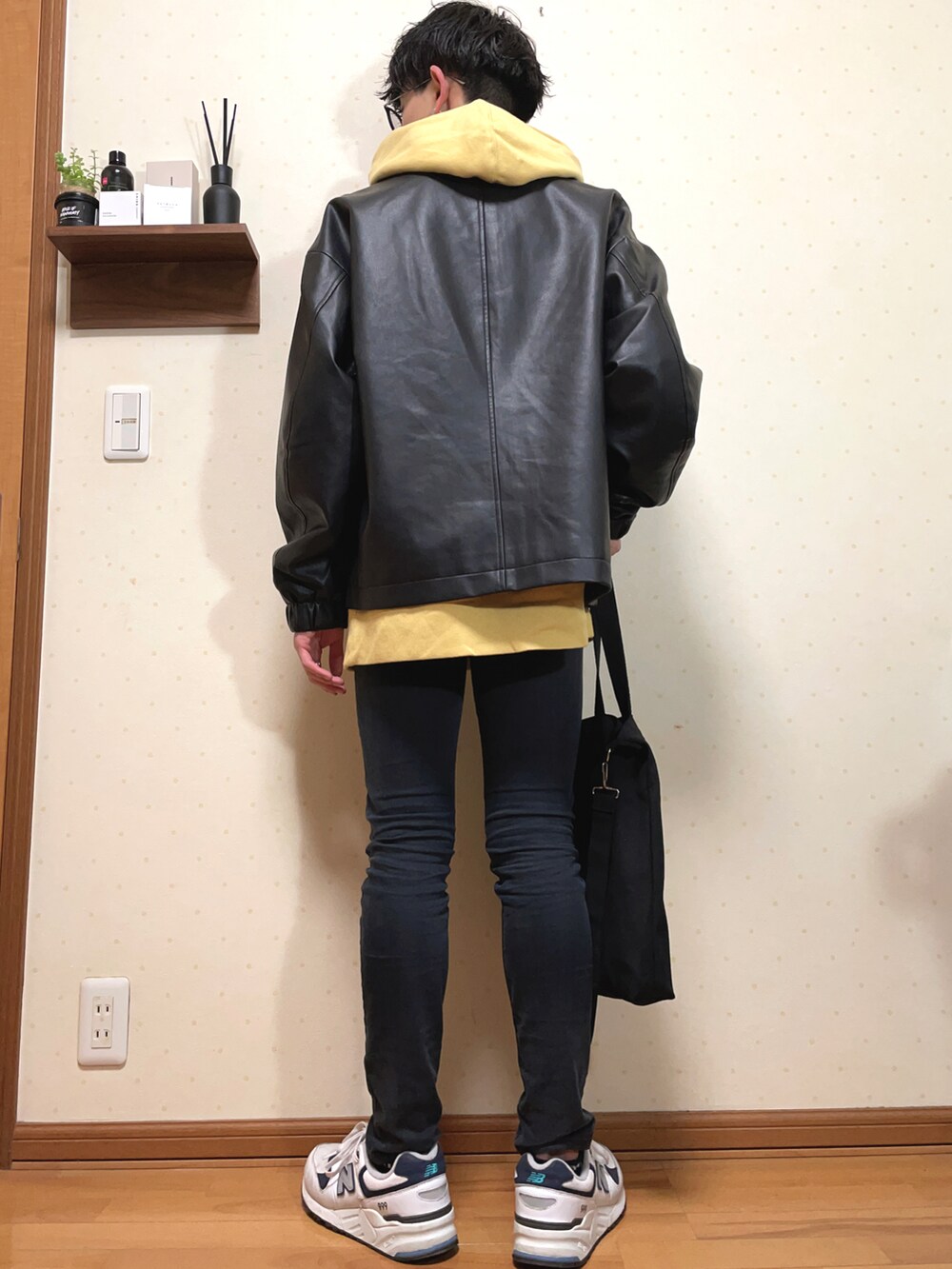 ブラック系のブルゾン、イエロー系のパーカー、ブラック系のパンツを着用したメンズの春コーディネートの2枚目の写真