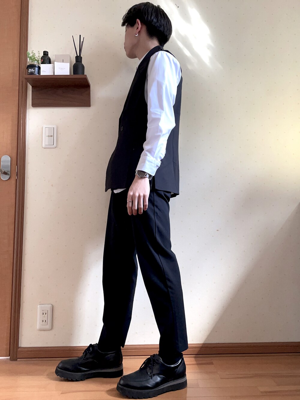 ブラック系のベスト、ホワイト系のシャツ/ブラウス、ブラック系のパンツを着用したメンズの春コーディネートの2枚目の写真