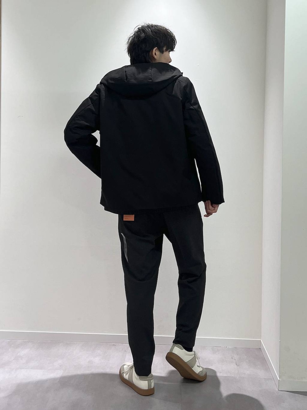 ベージュ系のスニーカー、ブラック系のブルゾン、グレー系のスラックスを着用したメンズの秋コーディネートの3枚目の写真