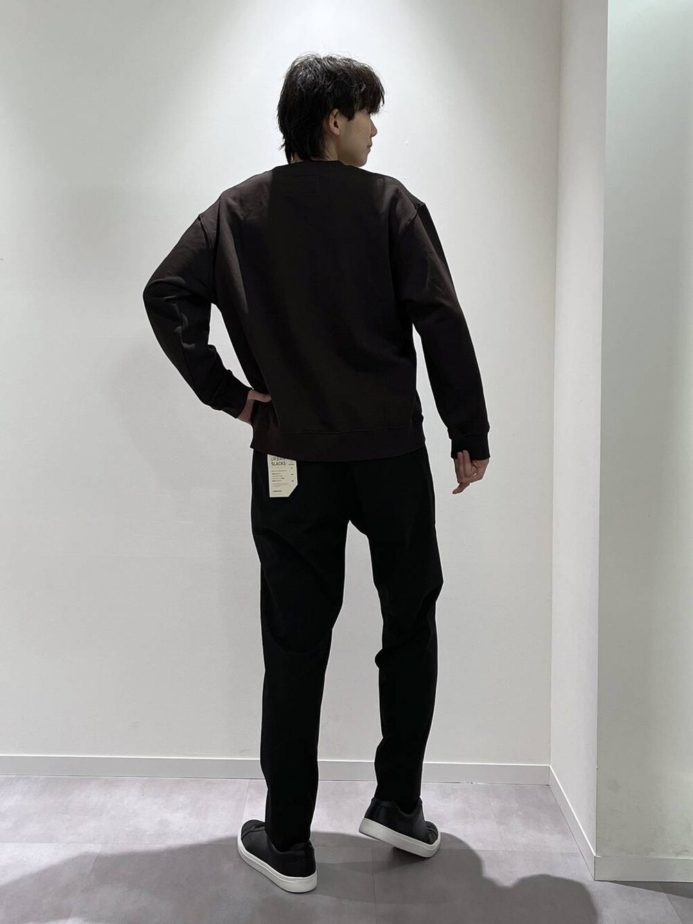 ブラック系のスラックス、ブラウン系のTシャツ/カットソー、ブラック系のスニーカーを着用したメンズの秋コーディネートの3枚目の写真