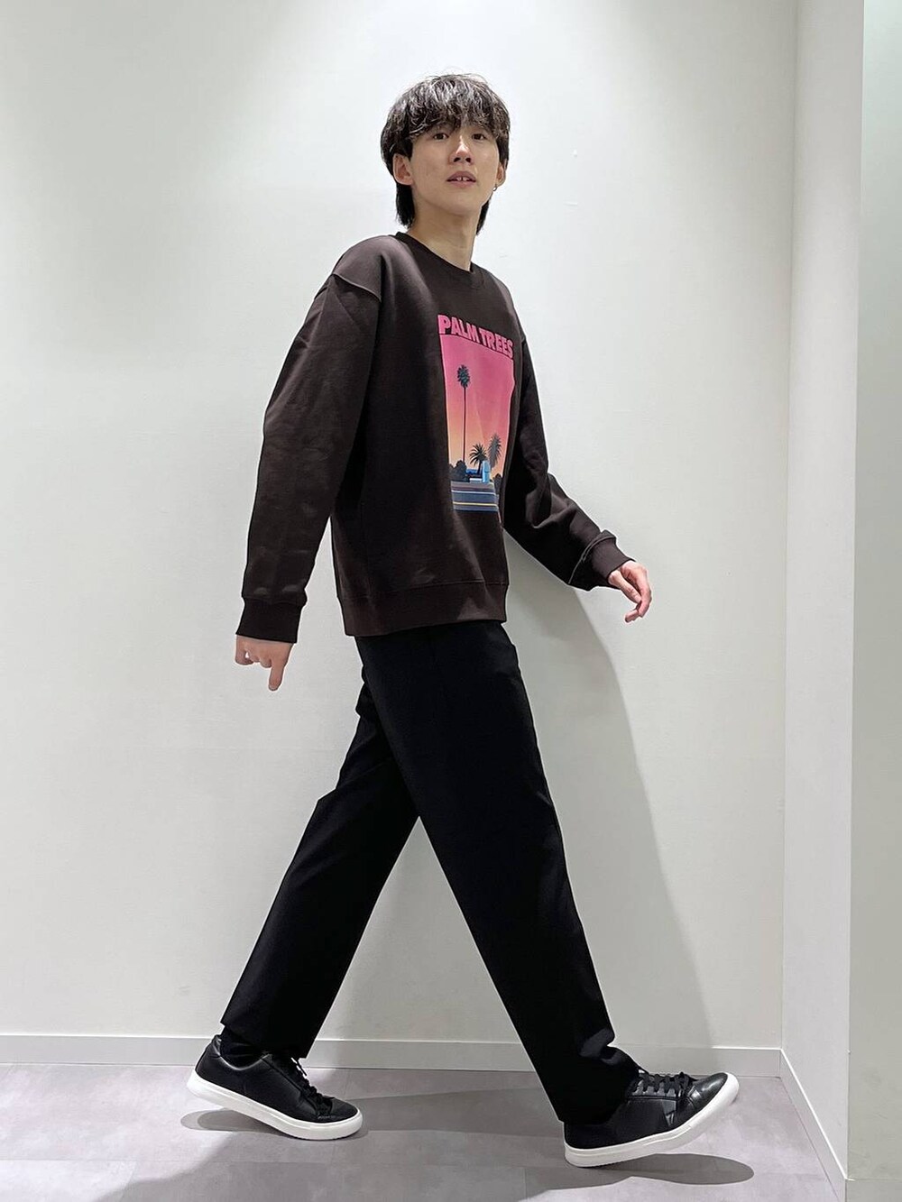 ブラック系のスラックス、ブラウン系のTシャツ/カットソー、ブラック系のスニーカーを着用したメンズの秋コーディネートの2枚目の写真