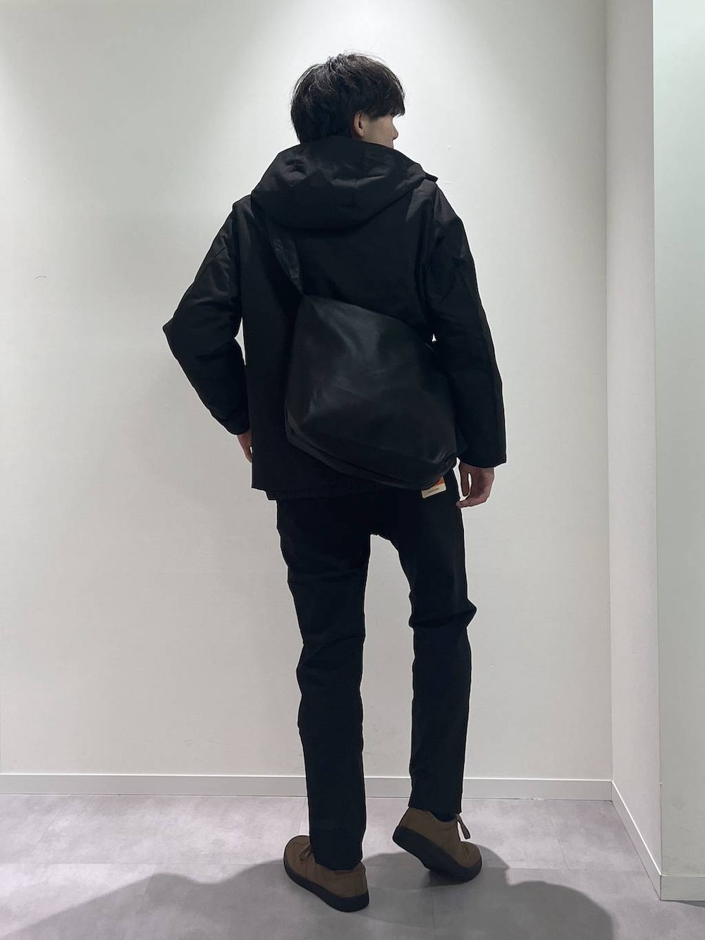 ブラウン系のスニーカー、ブラック系のショルダーバッグ、ブラック系のブルゾンを着用したメンズの秋コーディネートの3枚目の写真