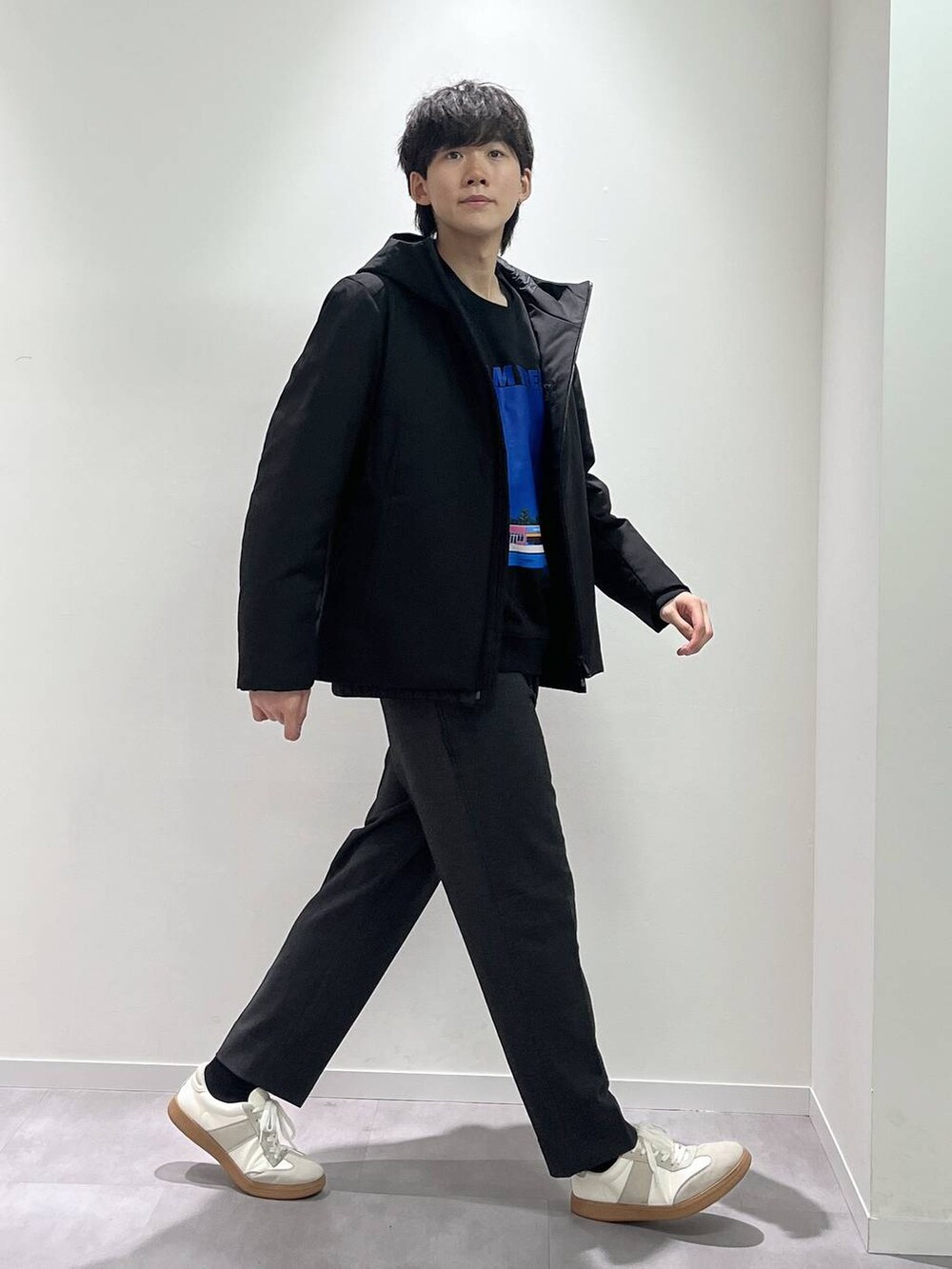 ベージュ系のスニーカー、ブラック系のブルゾン、グレー系のスラックスを着用したメンズの秋コーディネートの2枚目の写真