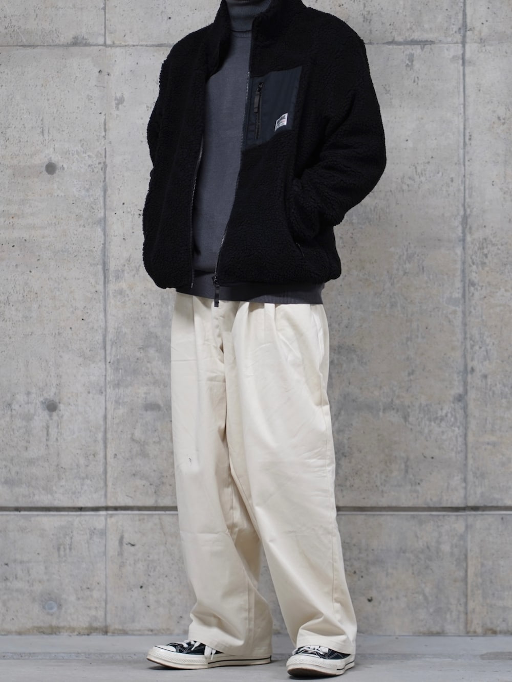 ブラック系のブルゾン、グレー系のニット/セーター、ホワイト系のチノパンツを着用したメンズの冬コーディネートの2枚目の写真