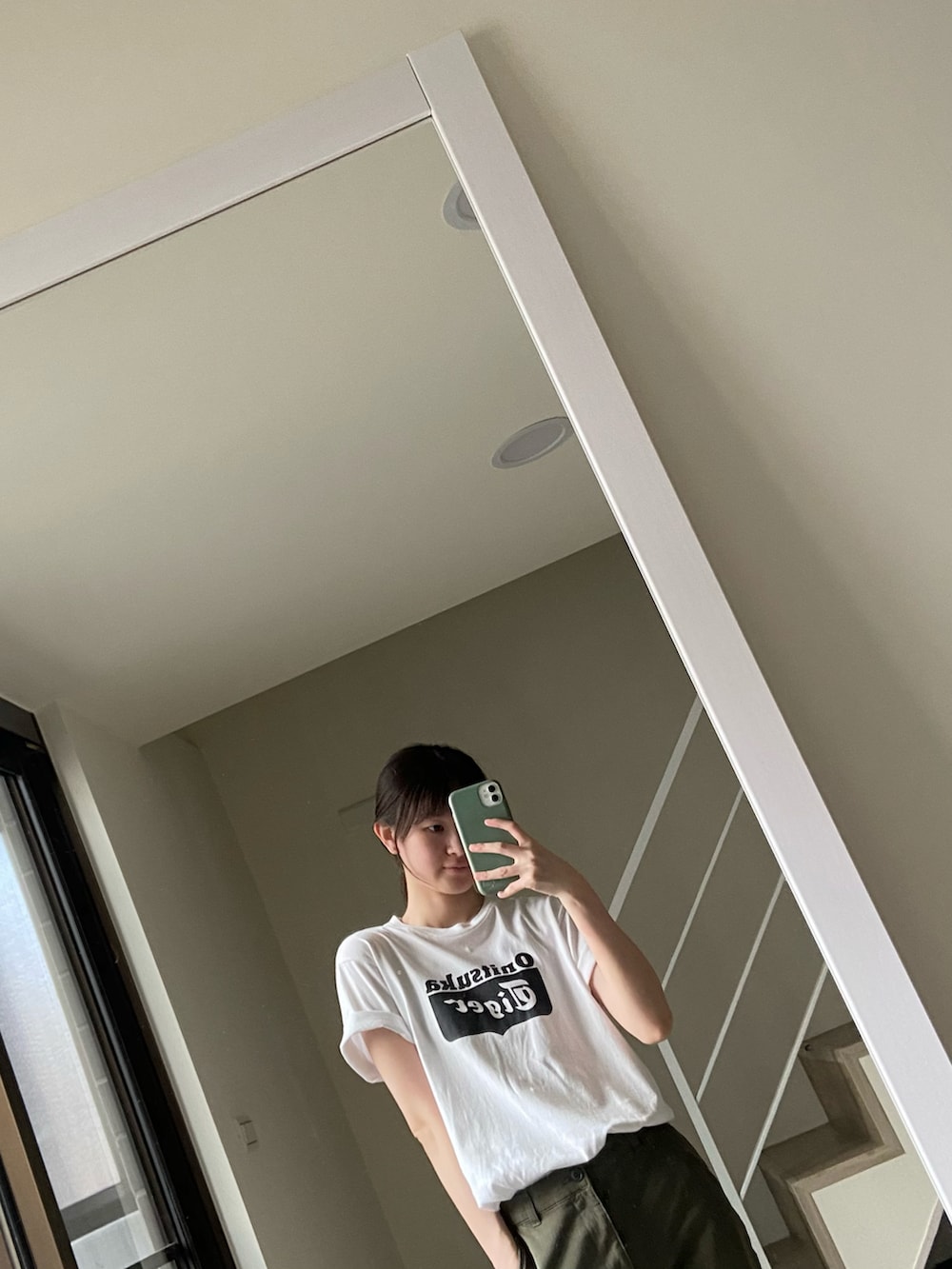 グリーン系のチノパンツ、ホワイト系のTシャツ/カットソー、ブラック系のバックパック/リュックを着用したレディースの夏コーディネートの4枚目の写真