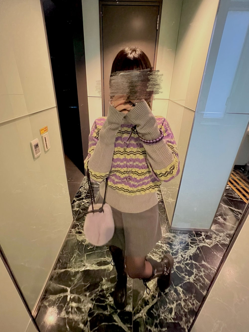 パープル系のバッグ、ブルー系のニット/セーター、ブラック系のブーツを着用したレディースの冬コーディネートの4枚目の写真