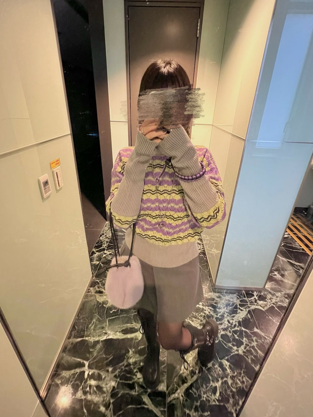 パープル系のバッグ、ブルー系のニット/セーター、ブラック系のブーツを着用したレディースの冬コーディネートの3枚目の写真