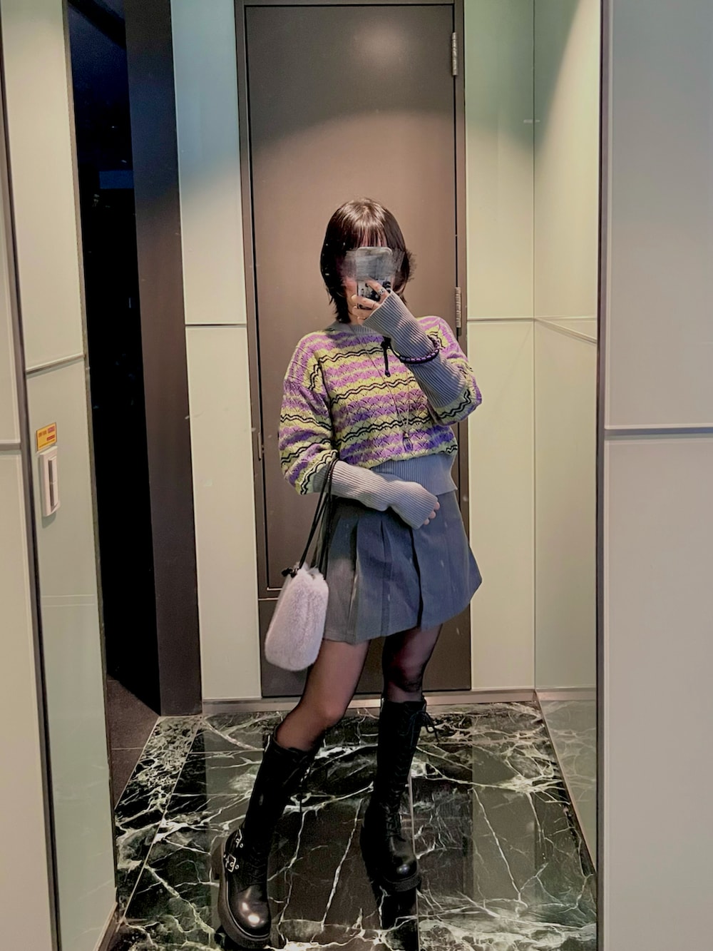 パープル系のバッグ、ブルー系のニット/セーター、ブラック系のブーツを着用したレディースの冬コーディネートの2枚目の写真