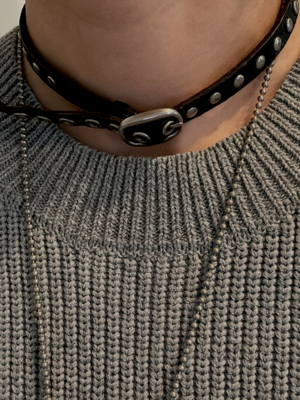 グレー系のニット/セーター、ブラック系のデニムパンツ、ブラック系のブーツを着用したレディースの春コーディネートの2枚目の写真