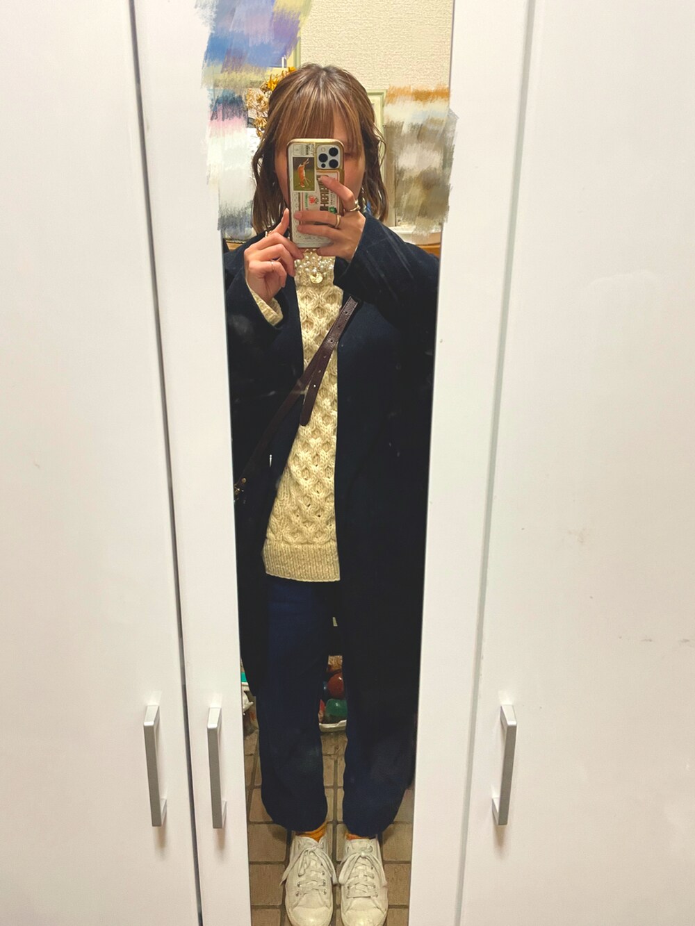 ホワイト系のスニーカー、ブラウン系のショルダーバッグ、ブラック系のジャケット/アウターを着用したレディースの冬コーディネートの2枚目の写真