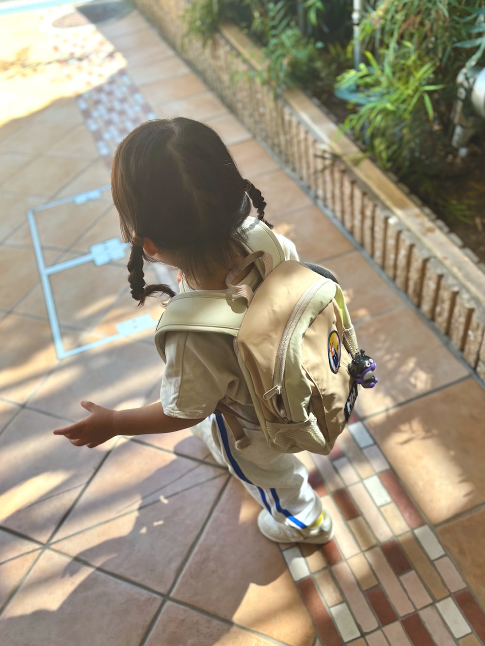 ベージュ系のスニーカー、ベージュ系のバックパック/リュック、ホワイト系のスウェットパンツを着用したキッズの秋コーディネートの2枚目の写真