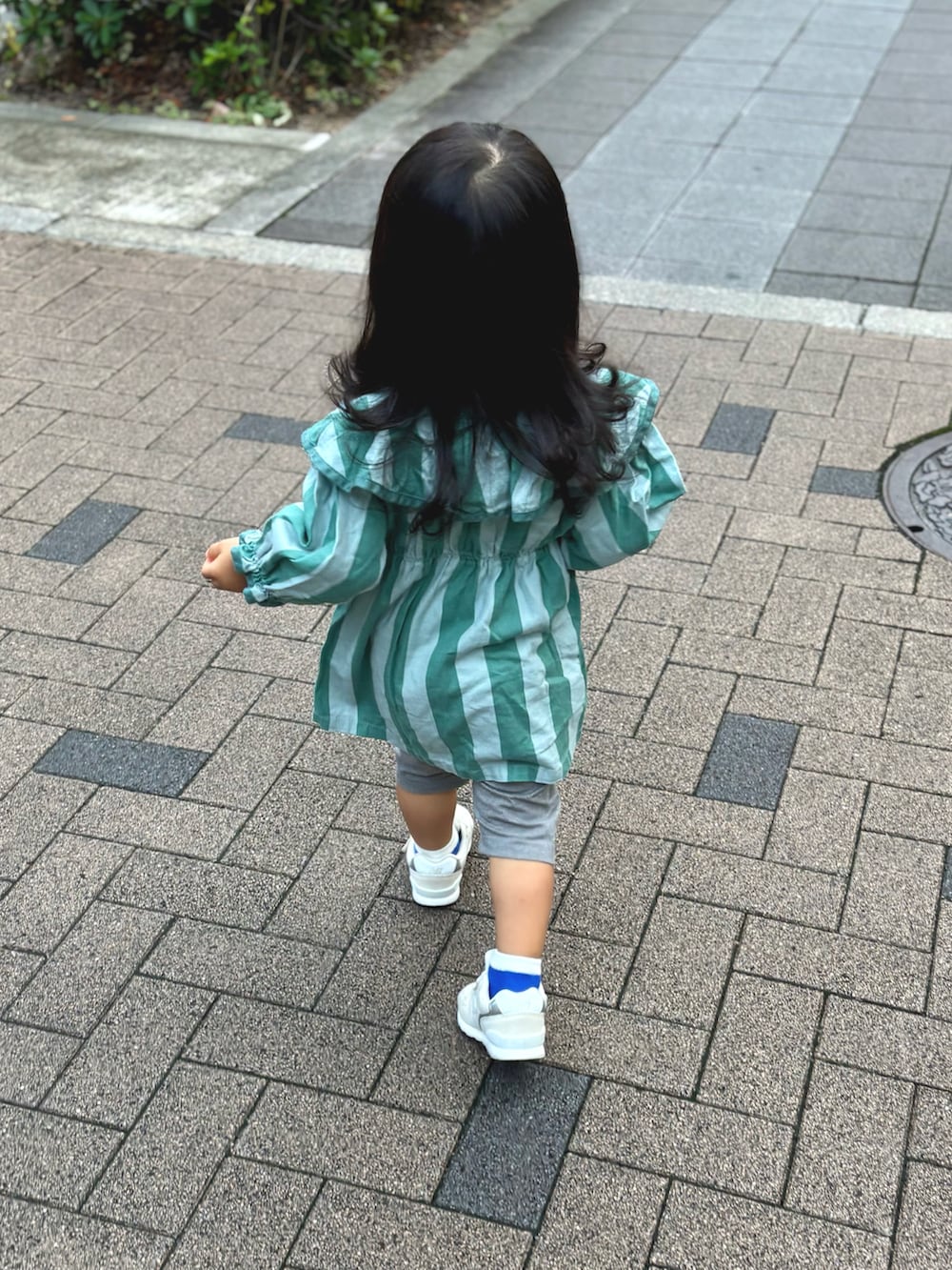 グリーン系のワンピース、ベージュ系のスニーカーを着用したキッズの秋コーディネートの2枚目の写真