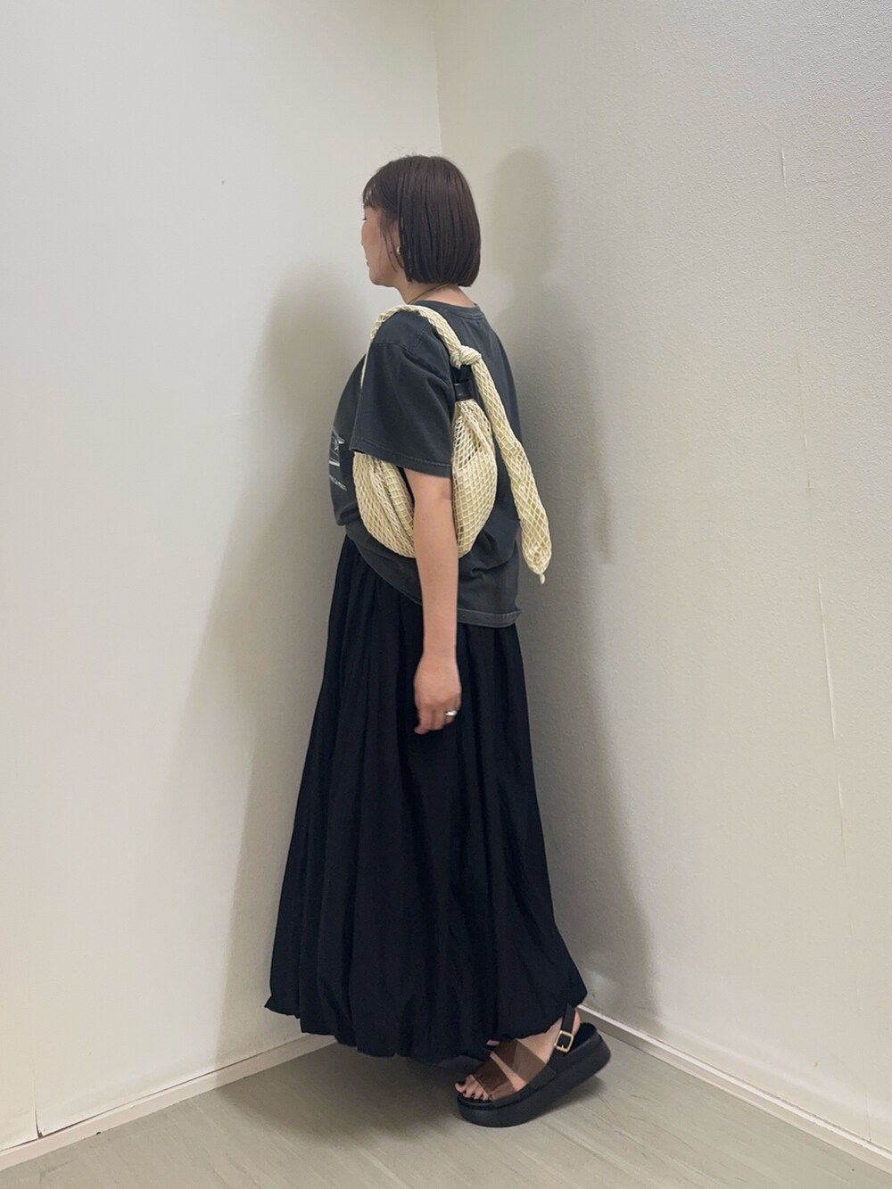 グレー系のTシャツ/カットソー、ブラック系のスカート、ホワイト系のショルダーバッグを着用したレディースの春コーディネートの4枚目の写真