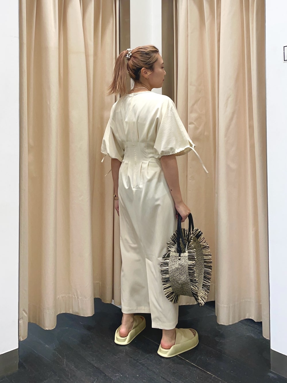 ホワイト系のワンピース、イエロー系のサンダル、ブラック系のハンドバッグを着用したレディースの春コーディネートの3枚目の写真