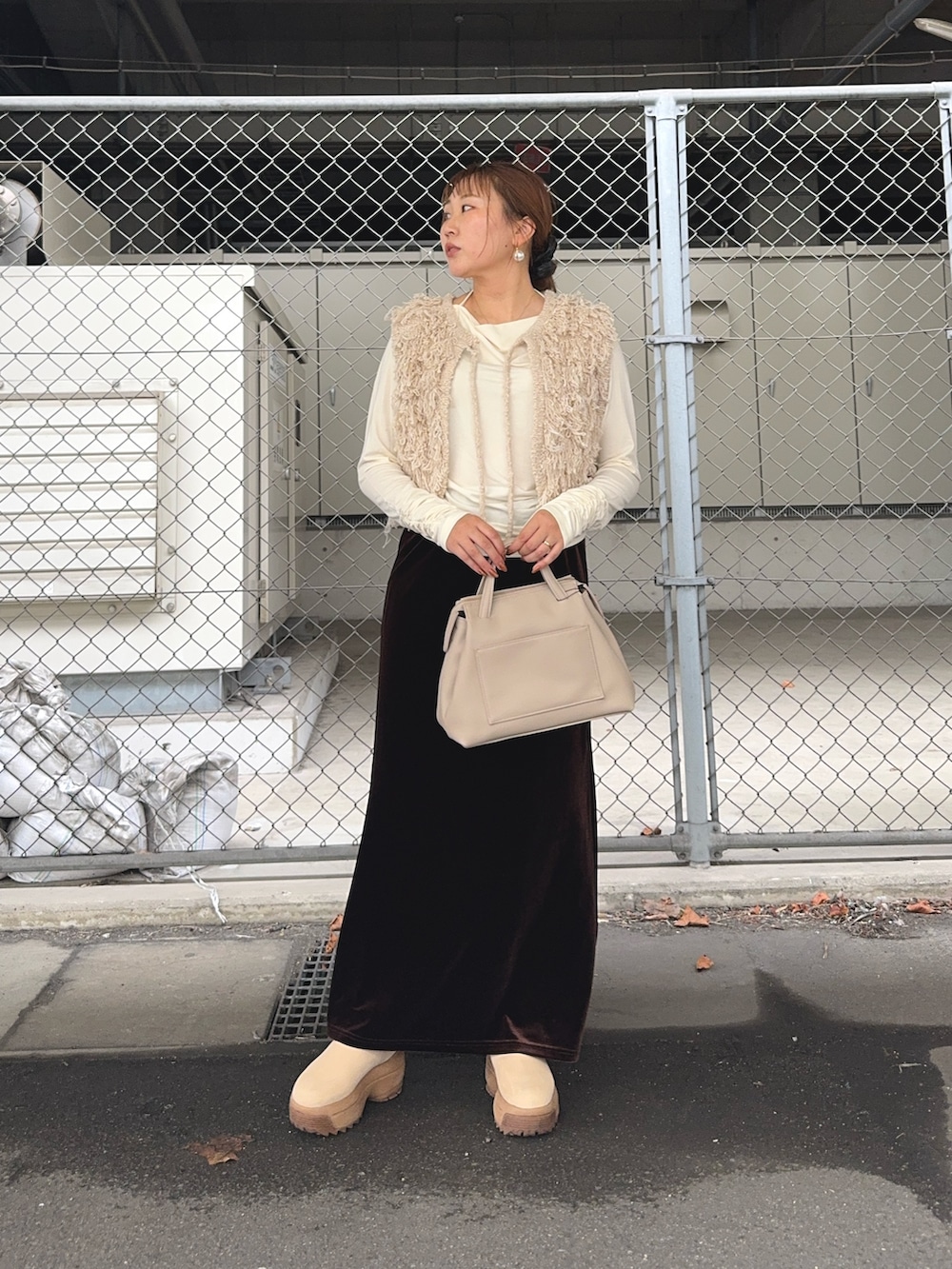 ブラウン系のスカート、ベージュ系のベスト、ホワイト系のTシャツ/カットソーを着用したレディースの秋コーディネートの3枚目の写真