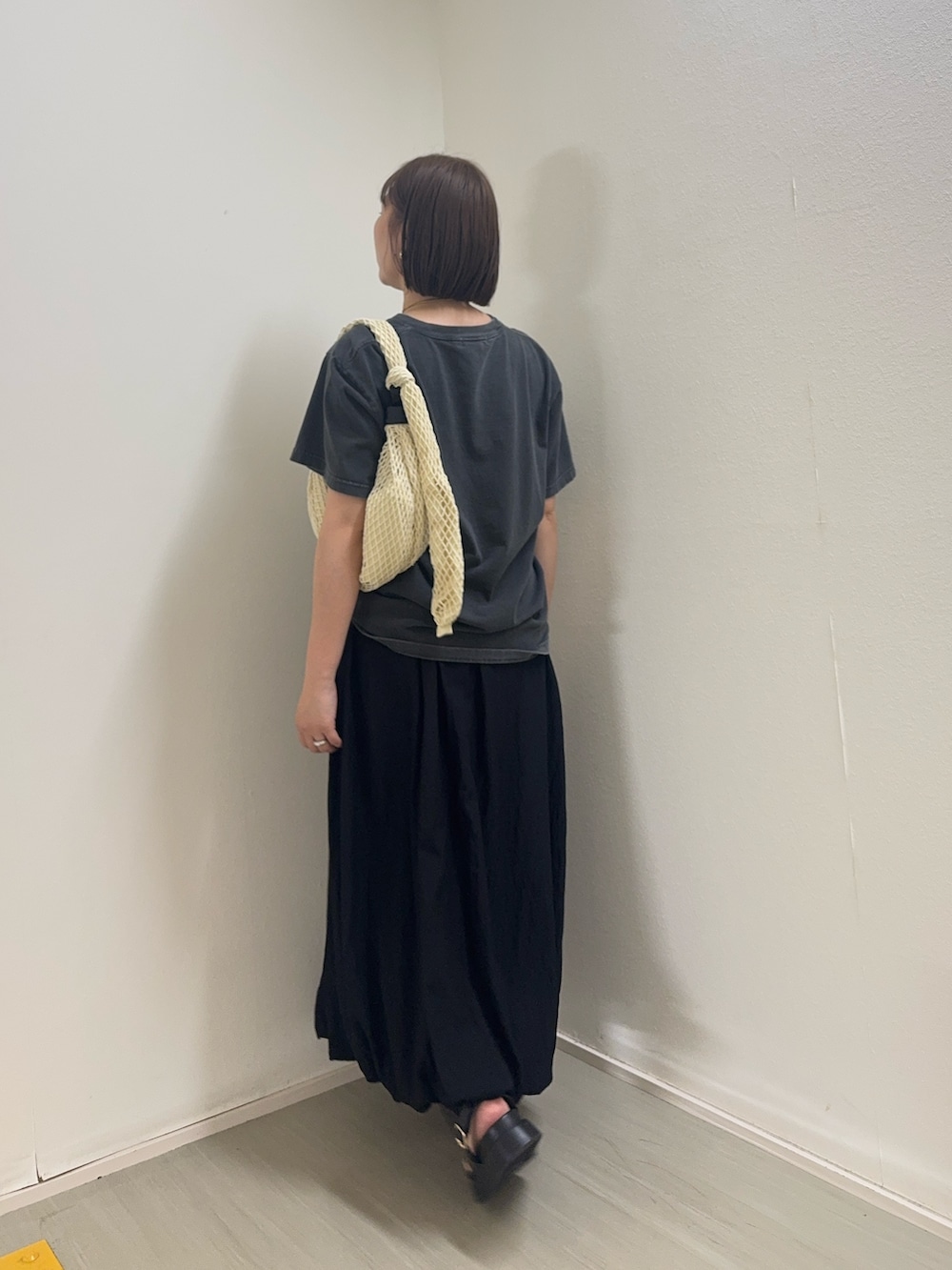 グレー系のTシャツ/カットソー、ブラック系のスカート、ホワイト系のショルダーバッグを着用したレディースの春コーディネートの3枚目の写真