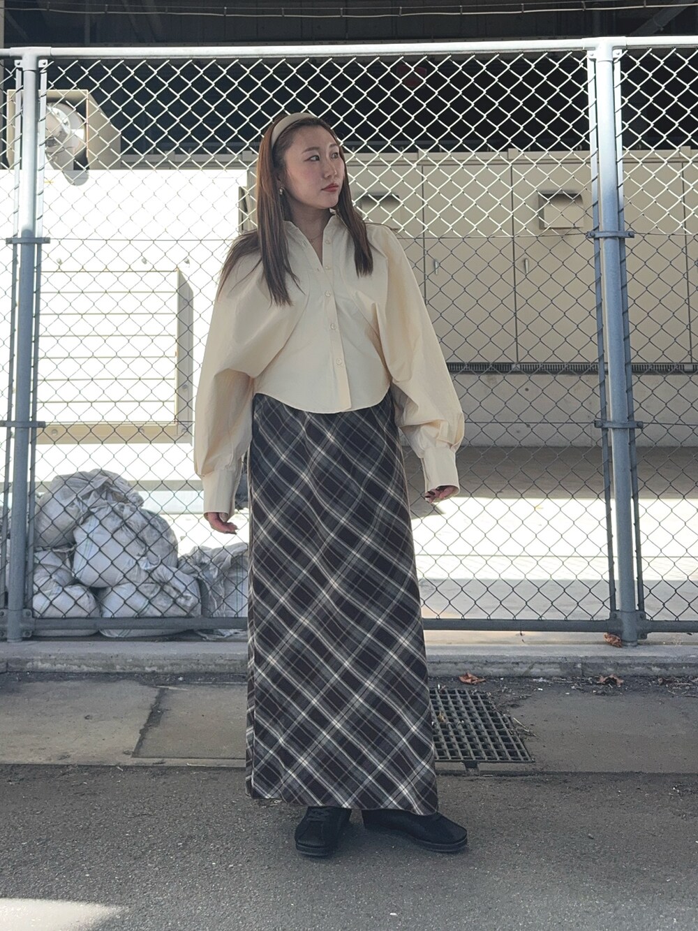 ブラウン系のスカート、ベージュ系のシャツ/ブラウス、ブラック系のスニーカーを着用したレディースの秋コーディネートの2枚目の写真