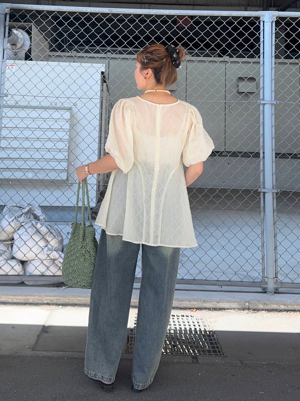 ブルー系のデニムパンツ、グリーン系のトートバッグ、ホワイト系のシャツ/ブラウスを着用したレディースの夏コーディネートの3枚目の写真