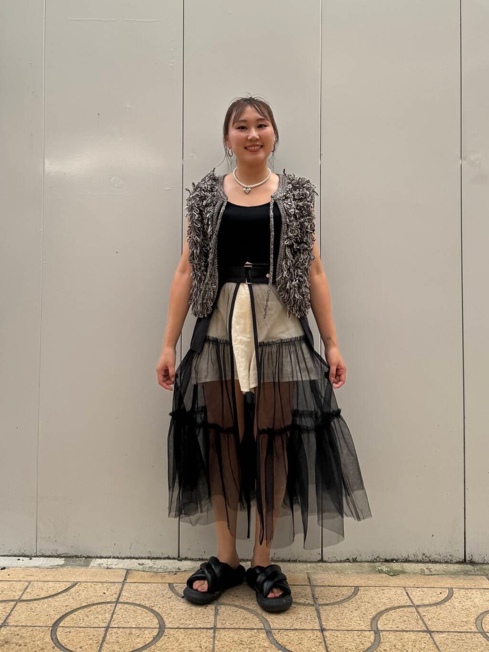 グレー系のスカート、グレー系のベストを着用したレディースの夏コーディネートの2枚目の写真