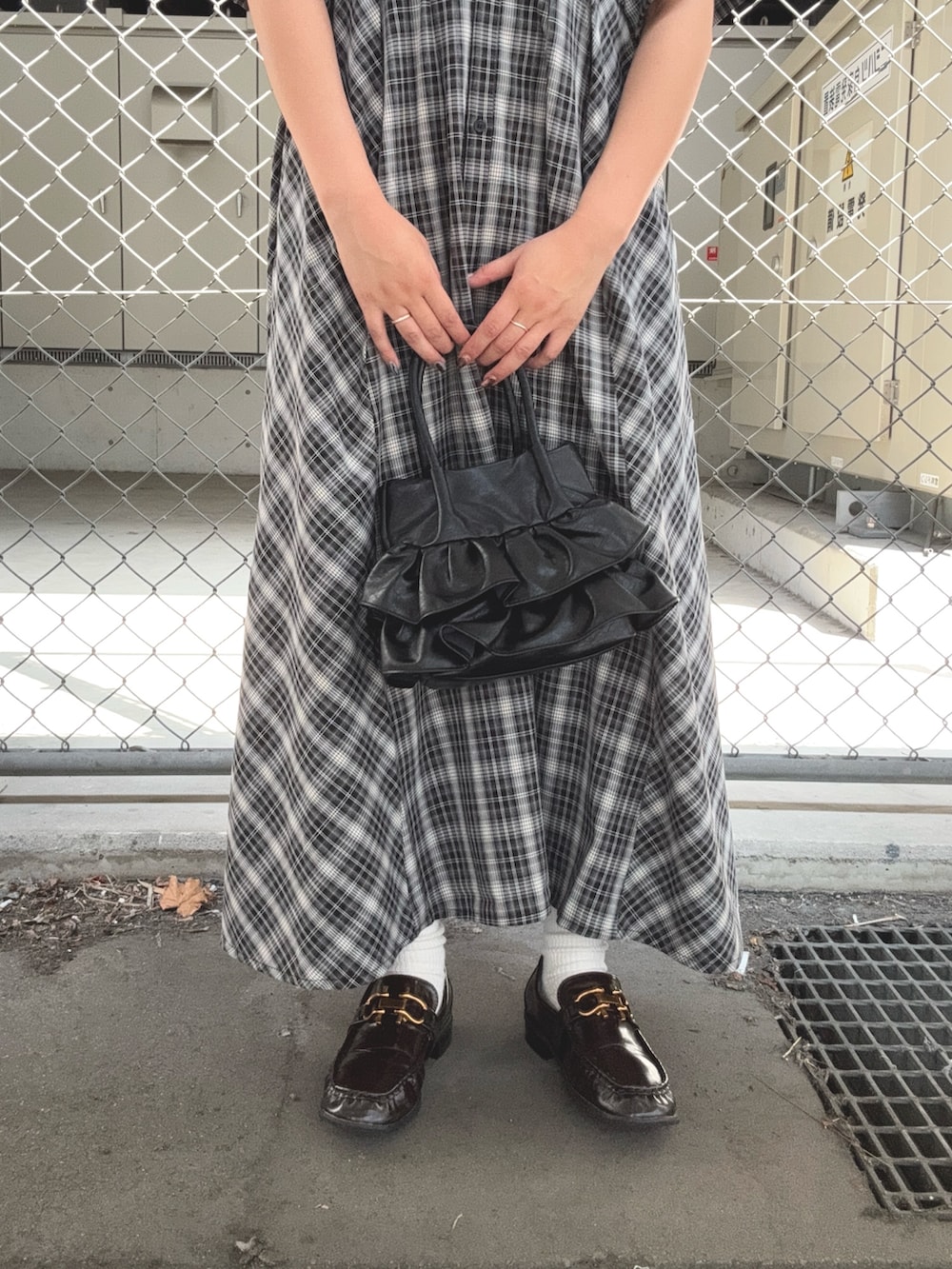 ブラック系のワンピース、ブラウン系のローファー、ブラック系のハンドバッグを着用したレディースの夏コーディネートの6枚目の写真