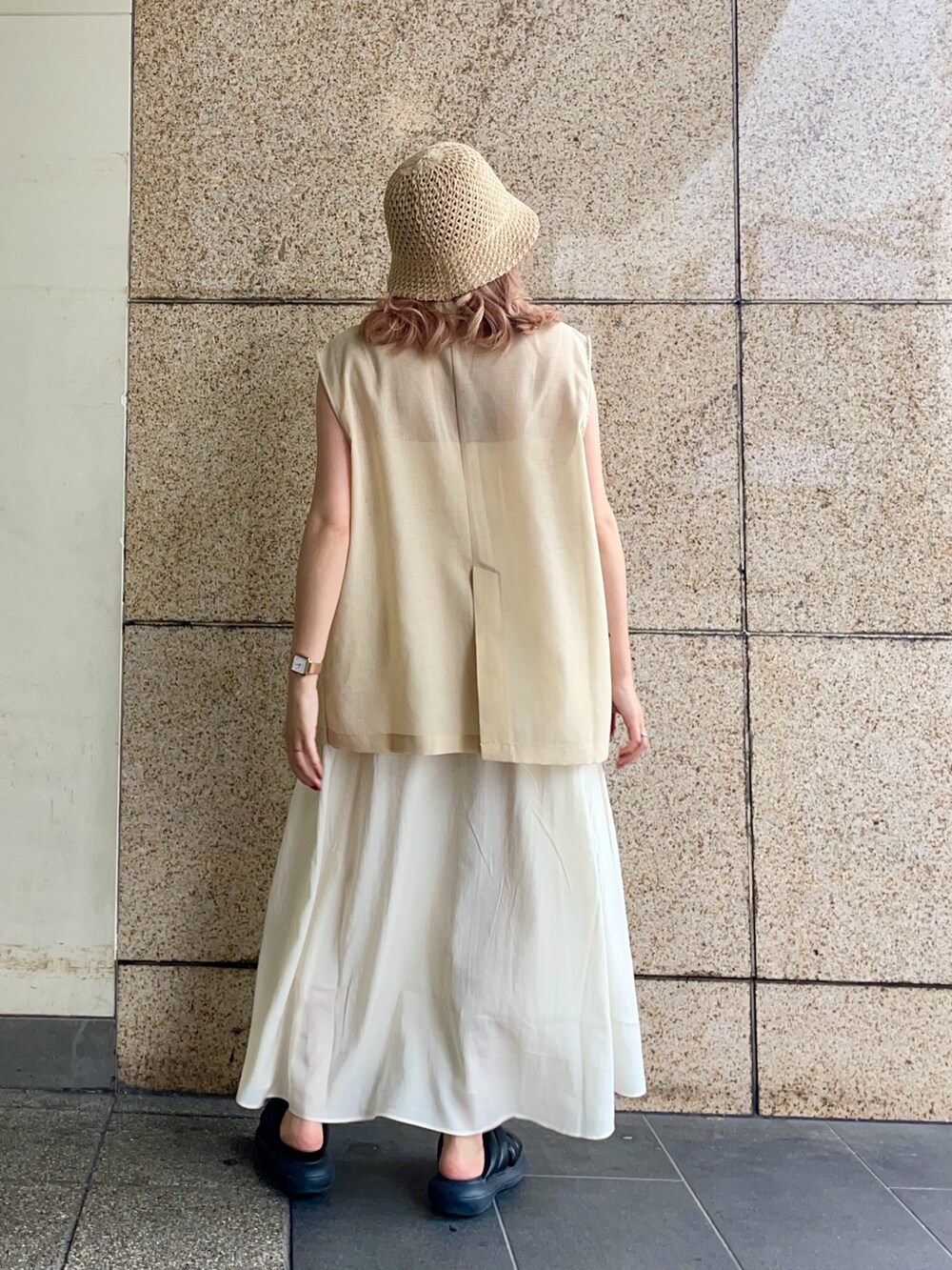 ベージュ系のベスト、ホワイト系のワンピース、ベージュ系のハットを着用したレディースの春コーディネートの3枚目の写真