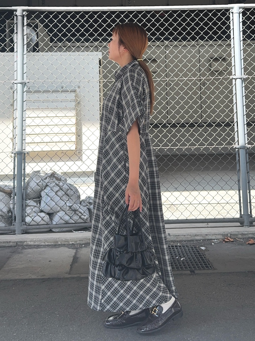 ブラック系のワンピース、ブラウン系のローファー、ブラック系のハンドバッグを着用したレディースの夏コーディネートの3枚目の写真